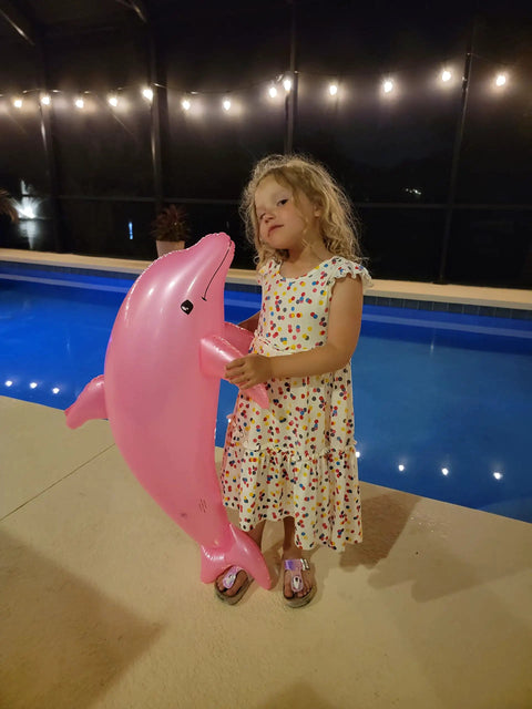 Child holding Massive 40 Inch Pearlized Dolphin Inflatable Pool Toy For Beach And Poolside Fun Pink 3 Pack Centerpiece Decor