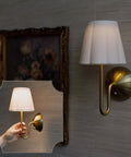 BSFHKLA Cordless Rechargeable Wall Sconce with Scalloped Fabric Shade and Remote, Brass Finish, USB, Dimmable LED Lighting(WhiteVelvet) in use with hand holding lamp.