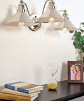 Welton 25.5 Inch Three Light Modern Farmhouse Vanity Light With Funnel Shades Gooseneck Industrial Wall Sconce on wall above books