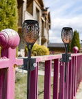 Heavy Duty Deck Torch Clamp Set Black Metal Rail Mounts For Outdoor Torches Universal Porch Rail Clamp Accessory Weatherproof Galvanized Steel Anti Rust Two Pack Fits Railings And Poles For Easy Deck Lighting installed on pink railings.