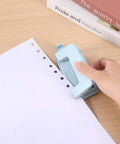 Using Two-Hole Paper Puncher With Adjustable Guide and Labor-Saving Handle on white paper, showcasing 0.23 inch holes, blue