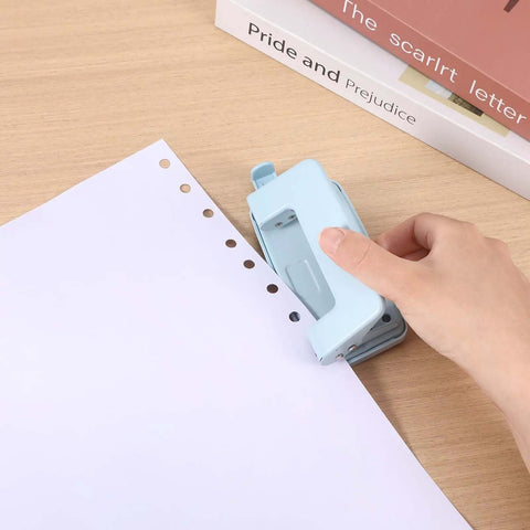 Using Two-Hole Paper Puncher With Adjustable Guide and Labor-Saving Handle on white paper, showcasing 0.23 inch holes, blue
