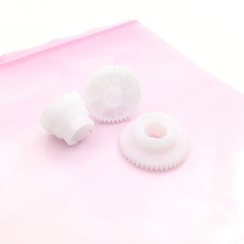 Three white gears from Five Set Change Tractor Idle Gear Kit For OKI Okidata ML320 ML321 ML390 ML391 ML420 ML421 ML490 ML491 ML520 ML521 ML590 ML591 Printers OEM Codes 51215901 51228001 51228101 51238501 on a pink surface