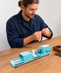 Super Compact Mini Wood Lathe Machine Featuring 96W Motor And Seven Adjustable Speeds Up To 9000Rpm For Precision Turning Punching Engraving Cutting Grinding Polishing Ideal Diy Projects With Lightweight Metal Body And Quick Change Chuck For Easy Setup, used for bead crafting by a man on a wooden table.