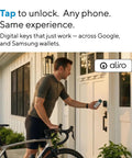 A man unlocking a smart door lock with a smartphone while holding a bicycle, showcasing modern digital access options.