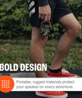 Person holding Clip 4 Portable Mini Bluetooth Speaker with carabiner, showcasing compact and rugged design for adventures.