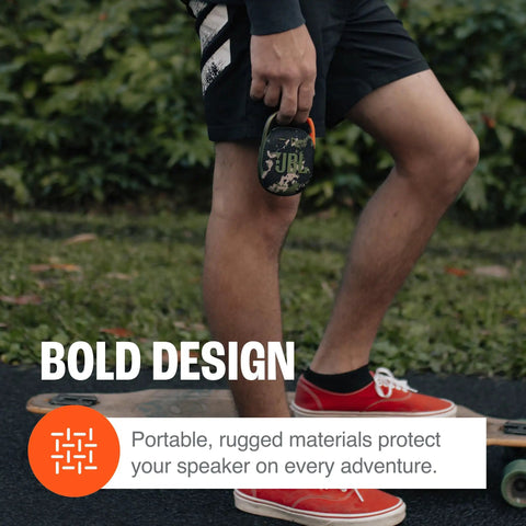 Person holding Clip 4 Portable Mini Bluetooth Speaker with carabiner, showcasing compact and rugged design for adventures.