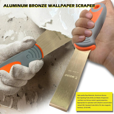 Aluminum bronze wallpaper scraper with ergonomic handle scraping textured wall surface.