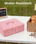 Pink Cash Box With Money Tray And Key Lock for cash till outdoors in rain at market with bread and coins visible nearby.