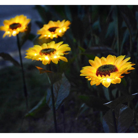 Upgraded 4 Flower Solar Sunflowers With Fairy Light Petals For Yard Decor at night glowing in a garden.