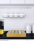 Bamboo Coffee Pod Organizer For Drawer Or Countertop Space Saver that holds 24 to 36 K cups on a kitchen counter next to a coffee maker.