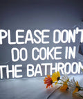 White neon sign reading 'PLEASE DON'T DO COKE IN THE BATHROOM' with flowers, acrylic backboard with pre-drilled holes, USB powered.