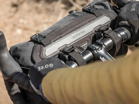 Cyclist with Front Loader 8L Waterproof Handlebar Bike Bag for Bikepacking, mounted on handlebars, rugged and weatherproof.