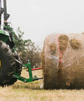 Dual Design Gooseneck Tractor Trailer Hitch With Hay Bale Spear Charcoal Frame Two Inch Receiver Mount And Two Five Sixteenth Inch Gooseneck Ball in use lifting a large hay bale