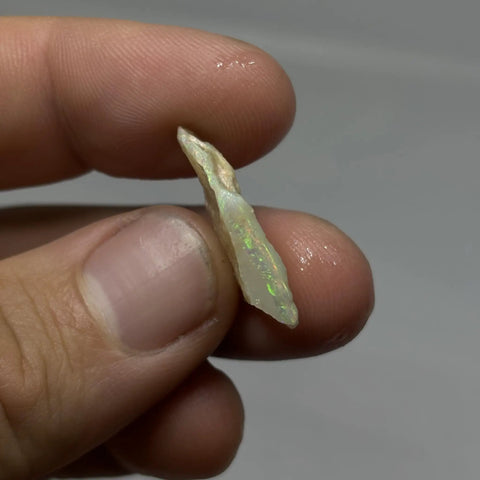 Person holding raw opal cutting material from Coober Pedy, highlighting multicolor patterns for jewelry making.