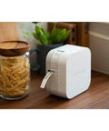 Total Game Changing Smartphone Color Label Maker Featuring Bluetooth Wireless Sync prints a label in a cozy kitchen setting.