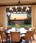 Black Farmhouse Wagon Wheel Chandelier With 10 Lights 31.5 Inch in dining room over round table at sunset