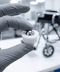 Close-up of a hand holding a 12pcs Steel Ball Transfer Caster with Nylon Housing, 0.7x0.5in, for wheelchair use.