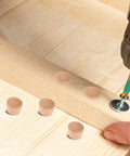50 Pack Wooden Button Top Plugs for Furniture Holes beside a wooden table being assembled with screws and a drill