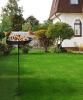 Sturdy Standing Bird Feeder Bowl On A 29.1 Inch Iron Stand, Detachable Outdoor Decor For Garden, Backyard, Patio Or Deck, Totally Built For Attracting Birds And Easy To Refill, Rust Resistant And Durable. Feeding birds in a garden setting.