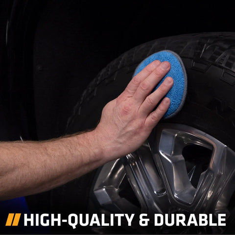 Hand using blue 5-inch microfiber pad on tire, Four Pack Five Inch Blue And Gray Microfiber Polishing Pads For Car Detailing Smooth Even Application Of Wax Polish And Tire Shine Each Pad Is Soft Yet Durable For Versatile Auto Care Tools.