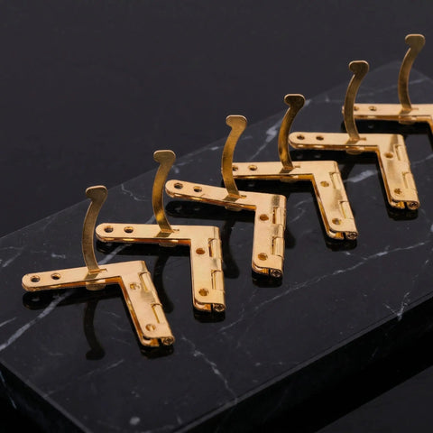 Gold iron Dope 92 Degree Quadrant Hinges For Wooden Boxes 20-Pack on black surface, showing 8-hole design