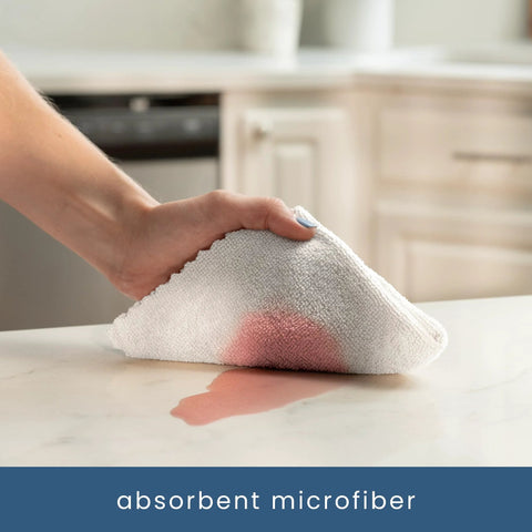 White microfiber cleaning cloth; close-up of hand wiping a kitchen counter.