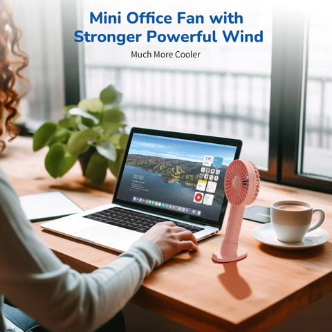 Handheld Portable Fan With 4000mAh Rechargeable Battery And 10 Hour Battery Life on a desk beside a laptop