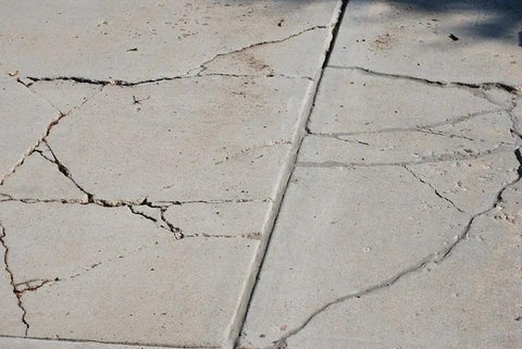 Concrete slab with visible cracks needing Slab Concrete Crack Repair Sealant Gray 10.5 Oz Cartridge Easy To Use Diy Friendly Kit.