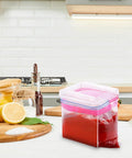 2 Pack Acrylic Food Prep Bag Holder Stand on kitchen counter holding a bag with red sauce.