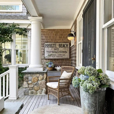 Portside Wall Sconce In Oil Rubbed Bronze And Antique Brass Finish with prismatic glass shade on a cozy porch wall