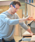 Heavy Duty Safety Glasses Bulk Pack With Clear Lenses And Durable Blue Frames Engineered For The Daily Grind No Nonsense Eye Guard Gear For Job Sites Labs And Working Crews worn by worker using saw.