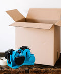Semi Automatic Heat Tape Cutter With Compact Desktop Packing Station And Lightweight Tape Holder For Quick Box Sealing And Top Shelf Shipping Hustle The Reliable Gadget For Smooth Tape Dispensing Routine Blue on a wooden surface next to an open cardboard box.