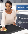 Person cleaning black Anti Fatigue Kitchen Mat Cushioned Comfort Rug For Standing Desk And Floor Water Resistant Non Slip Pad With Thick Foam Support