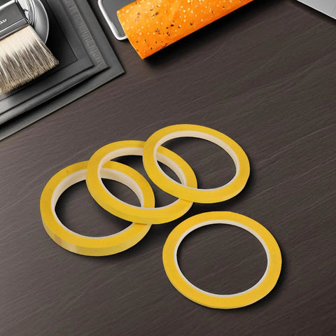 Four Pack Yellow Heat Resistant Paper Tape Featuring A Dang Tough Hold That Takes The Heat Without Breaking A Sweat arranged on a dark surface.