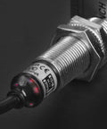 Close-up of M12 Inductive Proximity Sensor Switch PR12-2DO, cylindrical with 2mm sensing, flush mounted to a surface, CE certified.