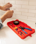 Close-up of red heavy-duty tool tray organizer for screws, nuts, bolts with grab handles on work surface, holding tools