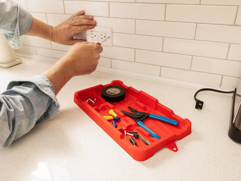 Close-up of red heavy-duty tool tray organizer for screws, nuts, bolts with grab handles on work surface, holding tools