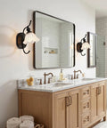 PUMING Black Wall Sconces Set of Two, Vintage Vanity Light Fixture with Flower Glass Shade illuminating a bathroom mirror.