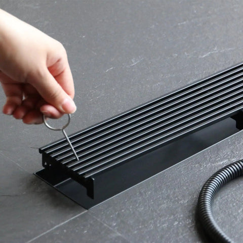 28 Inch Linear Shower Drain With Removable Wedge Wire Grate Matte Black 304 Stainless Steel Rectangle Shower Floor Drain For Bathroom CUPC Certified With Hair Strainer For Fast Easy Drainage shown with hand removing grate
