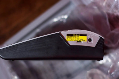 Side view of Pro Grade PT 2700 Desktop Labeling System with power port and notice label, silver and black design.