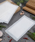 100 Piece Meat Absorbent Pads 4x7 Inch White Food Grade Soaker Pads for meat and fish packaging on kitchen surface with herbs