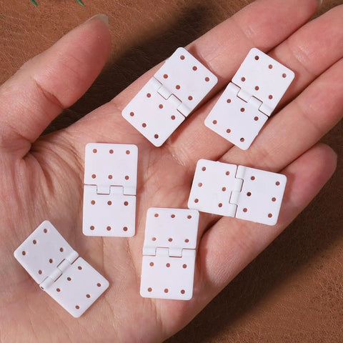 Folding Nylon RC Plane Hinges Kit for Fixed Wing Models 20 Pcs Square Leaf Hinges on hand showing 6 holes and white color.