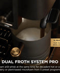 Top Shelf All In One Espresso Machine Featuring Built In Grinder And Hands Free Frother For Crisp Cold Brew And Fresh Drip Coffee Big Time Black Gold Edition frothing milk in a large jug.