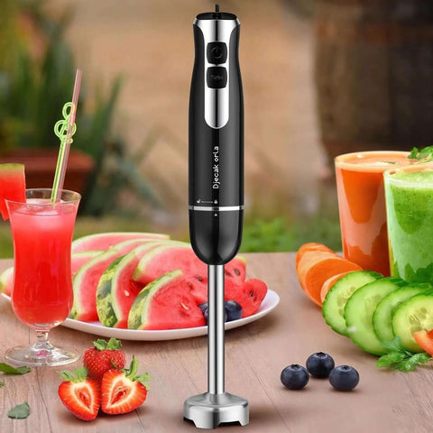 Badass 700W Immersion Hand Blender With 20 Precise Speed Options For Buttery Smooth Purees And Rapid Ingredient Prep In Any Home Kitchen Total Game Changer Black Finish on a kitchen table with fruits and drinks.