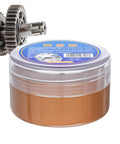 Copper Based Anti Seize Grease With High Temperature Protection jar next to metal gears, suitable for automotive and industrial use.