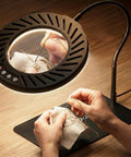 Person using 10X Magnifying Glass With Light And Stand, 144 LED Desk Lamp for embroidery work, highlighting stitch details.