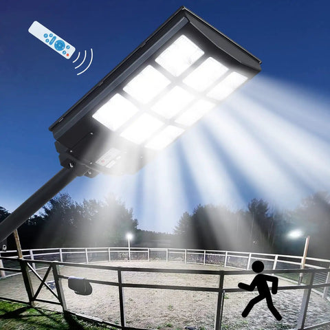 Outdoor Solar Street Light With Motion Sensor And Remote illuminating a fenced area at night, IP67 waterproof flood light for security.