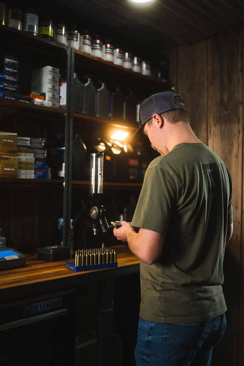 Man using bench top powder measure with improved funnel shape and static free aluminum body for accurate ammunition reloading