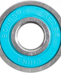 Close-up of Bones Reds skateboard bearing; turquoise inner race with metal outer ring